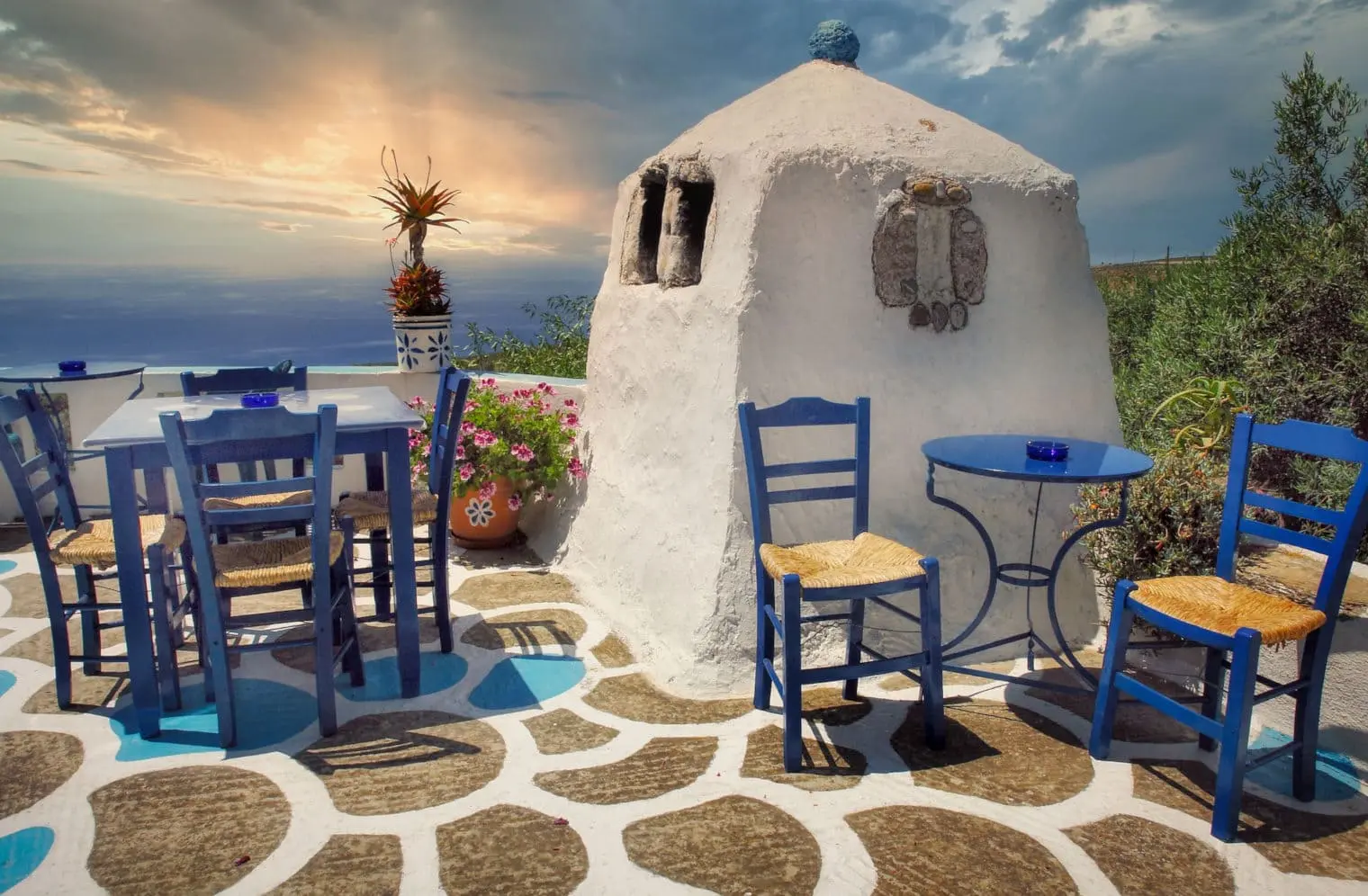 Traditional Greek taverna with blue chairs at sunset