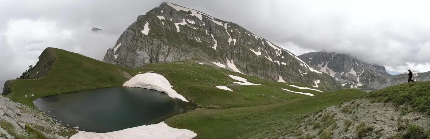 Hikers overlooking Dragon Lake in the Pindus mountains of Greece